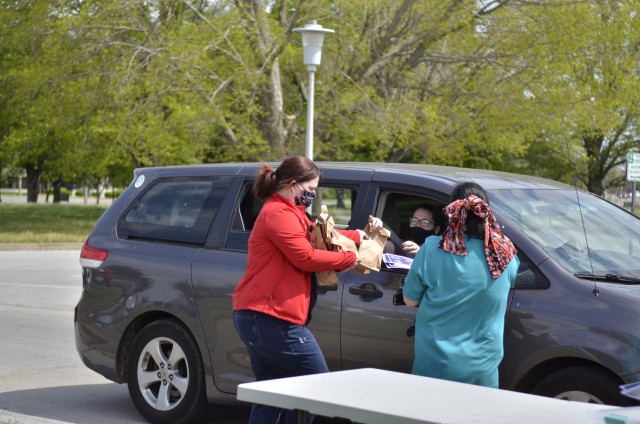 Adriene Laban, library technician, and Lisa Taylor, marketing coordinator for Fort Campbell Morale, Welfare and Recreation, hand out bags filled with crafts to Families, April 17 during the Grab-and-Go Brown Paper Bag Craft Giveaway at the Robert...