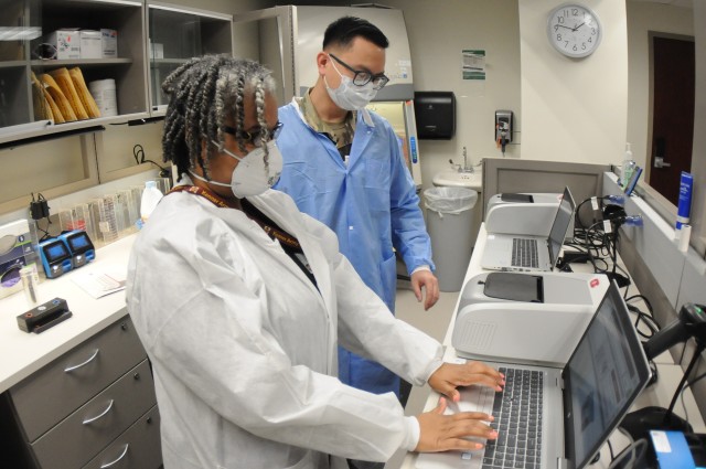 Kenner Army Health Clinic Laboratory Technicians Jean Ragland and Sgt. Vu Khuong train on the facility’s new equipment that’s capable of providing COVID-19 test results in about an hour. When fully operational, and with all needed supplies, the testing team will be able to process about 14-16 samples per day.