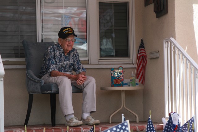 Lt. Col. Sam Sachs watches from his front porch as a parade drives by his home during a celebration in his honor in Lakewood, Calif. on April 26, 2020. The celebration and parade honored the World War II veteran’s 105th birthday. Sachs was an...