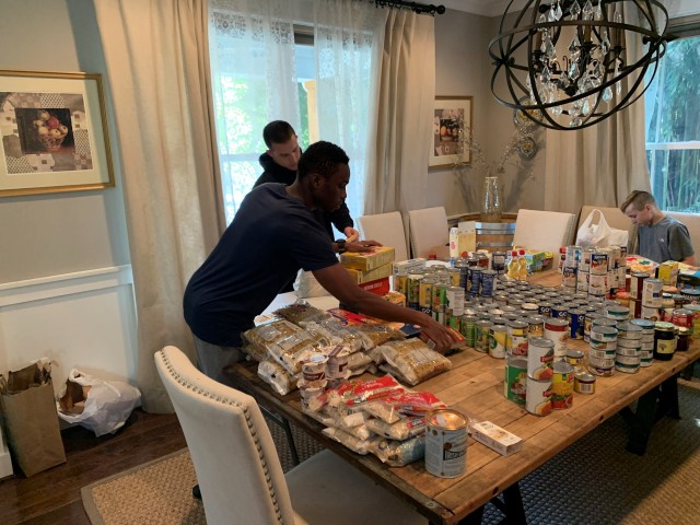 Class of 2023 Cadets Cobna Mannah, (front) an international cadet from The Gambia, and Jack Felgar (in back), of Falls Church, Va, work together to categorize food items as part of collecting food and donations to help many immigrants who lost their jobs.
