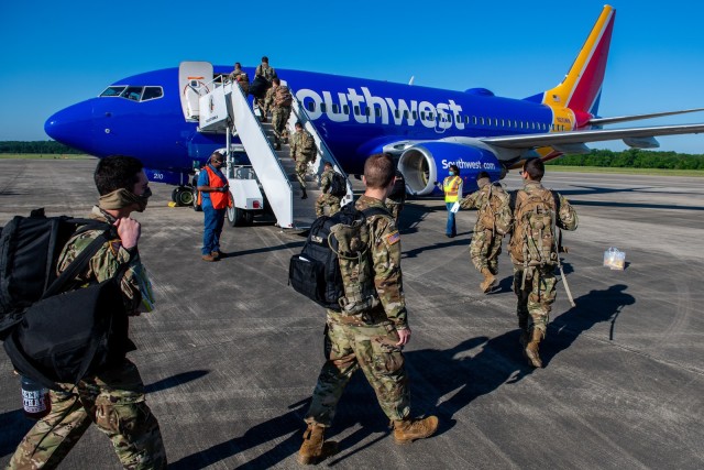 FORT BENNING, Ga. – At Fort Benning's Lawson Army Airfield April 14, Soldiers who recently graduated here from One-Station Unit Training for service with the Infantry or Armor, exercise social distancing and wear masks or other face coverings as they board an aircraft enroute to their first post-training duty station. Until earlier this month, OSUT graduates could not move to their next assignments under a Pentagon COVID-19 travel ban, but the Army later okayed their departures. Meanwhile, Fort Benning officials on April 28 announced they were lifting just a few of the many restrictions in place here since March as a precaution against COVID-19, and said those were a prelude to what could become a wider, phased removal of many other restrictions.