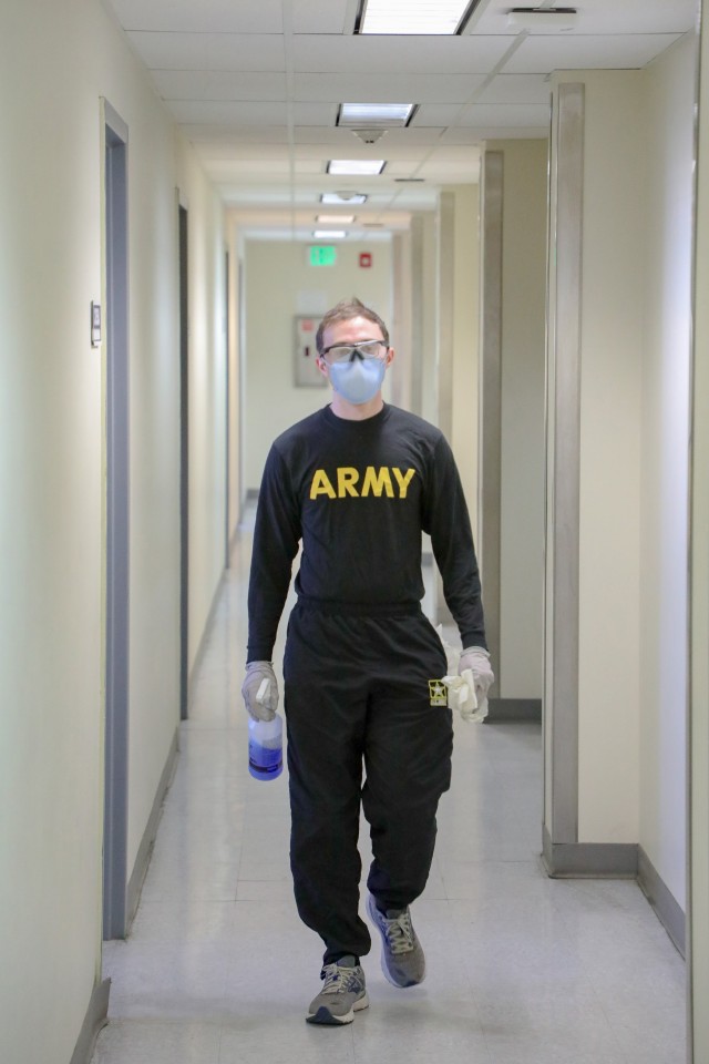 Pfc. Kyle Barrett cleans key points on doors and door frames on the thrid-floor hall of the quarantine building 3440 on Fort Wainwright as part of the daily routine, 24 April, 2020. The floors and key points are cleaned every three hours with bleach water. (US Army photo provided by Sgt. Christopher B. Dennis)