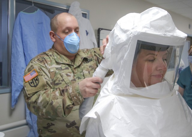 U.S. Army Sgt. Ryan Aker, a licensed practical nurse with the Medical-Surgical Unit at Landstuhl Regional Medical Center, assists U.S. Air Force Maj. April Oliver, assistant officer in charge, Intensive Care Unit, LRMC, with donning the Powered...