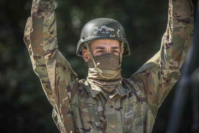 A trainee with 1st Battalion, 61st Infantry Regiment raises his arms while waiting to be harnessed at Fort Jackson’s Victory Tower. The trainee wears a cloth face covering as protection against the spread of COVID-19. Face coverings are one way Fort Jackson increased its protection posture during the pandemic. Fort Jackson leaders announced April 28 the post was preparing to relax some protective measures as the installation returns to ‘steady state’ operations. (Photo by Ms. Tori Evans)