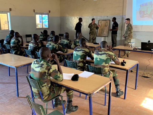 Chief Warrant Officer 3 Yagmur Saylak, top center, and Staff Sgt. Braxton Pernice, top right,  both assigned to 1st Security Force Assistance Brigade&#39;s Logistics Advisor Team 1610, discuss the importance of conducting preventive maintenance with Senegalese soldiers March 3, 2020, in Dakar, Senegal.
