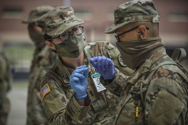 1st Lt. Katherine Rhea, deputy chief of Army hearing at Moncrief Army Health Clinic, instructs a trainee with 1st Battalion, 61st Infantry Regiment in the proper way to insert an ear plug. Both Soldiers are wearing protective face coverings in accordance with Army and Fort Jackson policy to help contain COVID-19. Fort Jackson leaders announced April 28 the post would begin transitioning to ‘steady state’ operations. (Photo by Ms. Tori Evans)