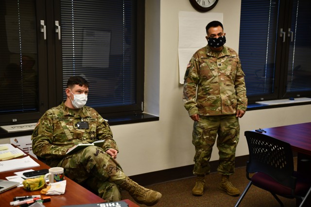 Capt. Michael Honsberger and Capt. Felipe Rodriguez, both medical logistics officers working with the Emergency Operations Cell at Kenner Army Health Clinic, take part in one of the daily briefings conducted at their temporary worksite in the Major General Kenner Conference Room (Photo by Lesley Atkinson, Kenner Army Health Clinic, PAO).