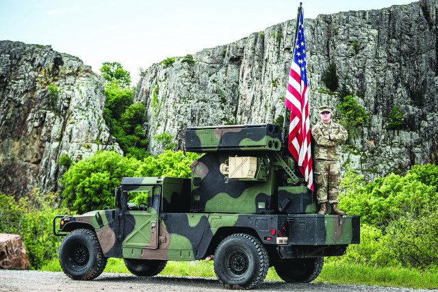 Capt. Jordan D. Henrickson stands with his flag on the back of an Avenger on Fort Sill, Okla., April 24, 2020. He is the found of American Flag Journey, a nonprofit organization.