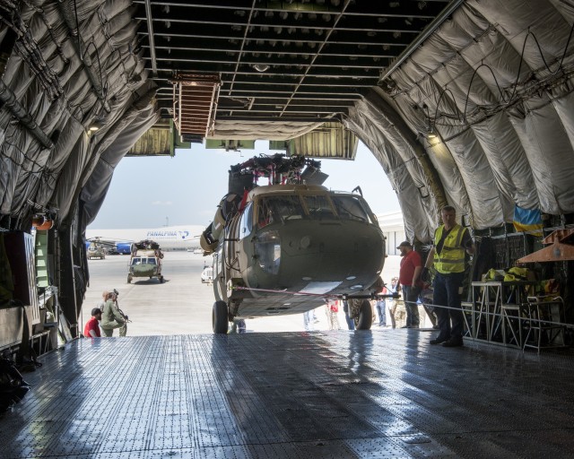 Team members from a Huntsville-based defense industry contractor, SES-I, who refurbished these two UH-60 Black Hawk helicopters for Afghanistan under a U.S Army Security Assistance Command foreign military sales case, upload the helicopters into...