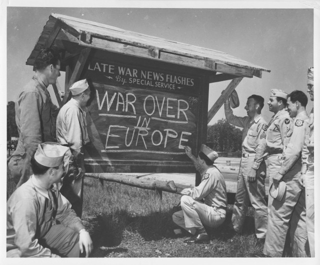 An Army private is shown breaking the news of the end of the war in Europe to other Soldiers after receiving an Associated Press news flash on it. 