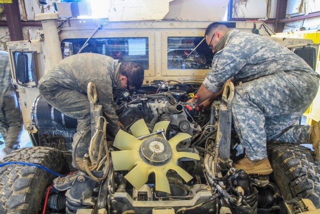 Spc. Anthony Bleakley, left, and Pvt. Pedro Munoz, right, Draught Troop, 1st Squadron, 32nd Cavalry Regiment, 1st Brigade Combat Team, 101st Airborne Division (Air Assault), recently work on a humvee engine within the maintenance bay of their motor pool. (U.S. Army Photo by Maj. Vonnie Wright)