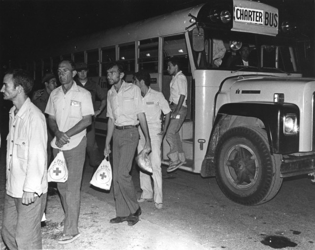 Cuban refugees step off a bus and into a holding area at Fort McCoy in 1980 after a ride from the La Crosse Municipal Airport. Fort McCoy served as a processing center for Cuban refugees from the Mariel Boatlift. (U.S. Army file photo by Mary Bower)