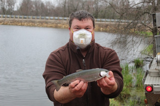 U.S. Fish and Wildlife Service (USFWS) employee Nick Bloomfield shows a rainbow trout he is stocking April 29, 2020, in Stillwell Lake on South Post at Fort McCoy, Wis. Approximately 15,000 rainbow trout were stocked at several lakes and ponds April 27-29, 2020, at Fort McCoy by the USFWS Genoa National Fish Hatchery of Genoa, Wis. (U.S. Army Photo by Scott T. Sturkol, Public Affairs Office, Fort McCoy, Wis.)