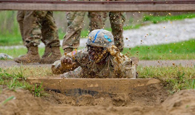 Cadet Ra’Shun Gerald, Norwich University, 4th Regiment Advanced Camp, splashes down into the mud at the start of the Hand Grenade Assault Course, Fort Knox, Ky., June 20, 2019. The course started with a high crawl under wires and through mud.
