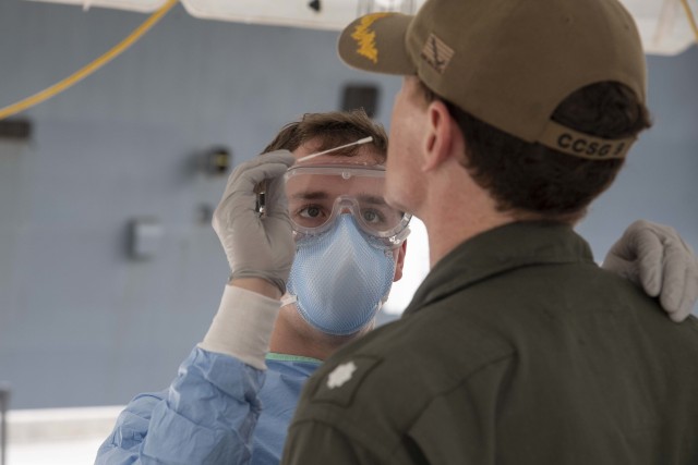 U.S. Navy Hospital Corpsman Hayden Runyon, assigned to 3rd Medical Battalion, 3rd Marine Logistics Group, takes a sample of a Sailor embarked aboard the aircraft carrier USS Theodore Roosevelt (CVN 71) to be tested for COVID-19 April 20, 2020....