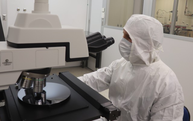 Miles Owen, a metrologist with the Army Primary Standards Laboratory, counts aerosol particles deposited onto a silicon wafer in the APSL clean room. The measurement is part of a research project to calibrate particle counters using large aerosol particles in the size range of bacteria, with application to environmental monitors and biological defense sensors.