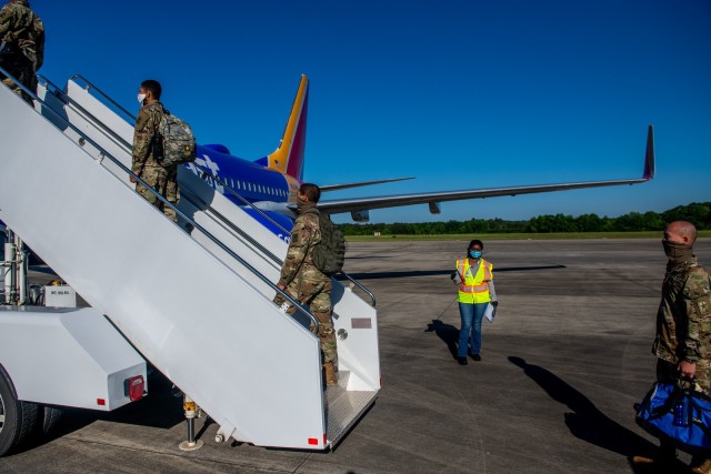 FORT BENNING, Ga. – At Fort Benning's Lawson Army Airfield April 14, Soldiers who recently graduated here from One-Station Unit Training for service with the Infantry or Armor, exercise social distancing and wear masks or other face coverings as they board an aircraft enroute to their first post-training duty station. OSUT graduates continue to depart Fort Benning for their next assignments. The U.S. Army's timetable for Soldiers moving to new duty stations was among topics covered in a May 12 video in which Fort Benning leaders discussed the recent easing of a few COVID-19 precautions here, and the prospect for further such actions in the weeks ahead and beyond.