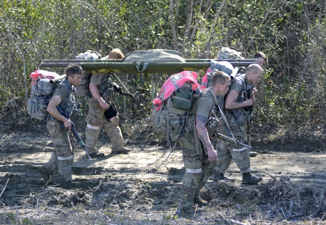 Candidates assigned to the U.S. Army John F. Kennedy Special Warfare Center and School carry a simulated patient through a muddy trail during Special Forces Assessment and Selection at Camp Mackall, North Carolina March 14, 2020. Candidates who...