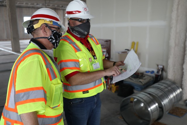 Ryan Field, left, project manager, and Jeremy Ayala, construction representative, both with the U.S. Army Corps of Engineers, Omaha, District, compare the plans May 12, for what will be an alternate care facility in Kalispell, Mont., to the...