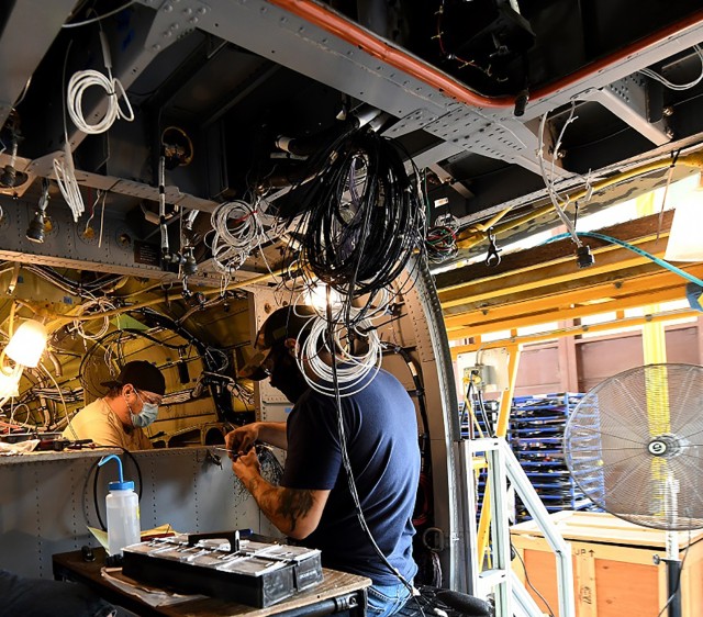 Jonathan Lopez (right) and Michael Lee, aircraft electricians in the assembly repair division at the Corpus Christi Army Depot, Texas, install the data concentrator units wiring as part of the UH-60L to UH-60V helicopter upgrade.