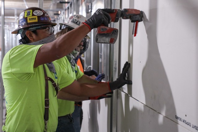 A contractor attaches a section of sheet rock to the frame of one of the pods May 11, of what will be an alternate care facility in Kalispell, Mont. The state of Montana requested FEMA to task the U.S. Army Corps of Engineers, Omaha District, to...