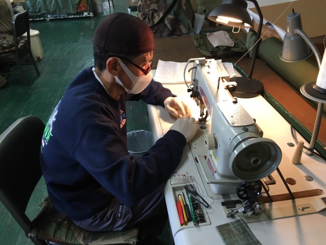 Kenji Uchida, parachute packer and repairer, Japan Support Team, Army Field Support battalion-Northeast Asia, Sagami General Depot, Japan, sews fabric face masks for Army Prepositioned Stocks-4. He and his cohorts Sato Ryuichi, Kakizaki Mutsuko, and Hoshina Tsuyoshi have produced more than 1,700 of the coveted masks for USFJ. (Photo by Chief Warrant Officer 4 Brian Perinon, Japan Support Team, AFSBn-NEA)