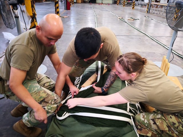 Staff Sgt. Angelito Froa, Spc. Ernie Ramirez and Sgt. Jodi Hough, 4th Quartermaster Theater Aerial Delivery Company, conduct a rigger check 7 in order to stow the lines of a G-11 Cargo Parachute System. (Photo by Chief Warrant Officer 2 Mervin Terre, 4th QM Co.)