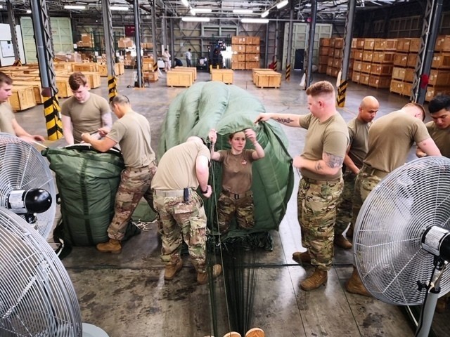 Parachute Riggers from the 4th Quartermaster Theater Aerial Delivery Company, pack G-11 Cargo Parachute systems for the Army Preposition Stocks-4 Aerial Delivery Operational Projects. (Photo by Chief Warrant Officer 2 Mervin Terre, 4th QM Co.)
