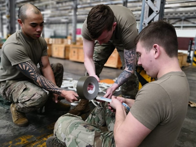 (From left) Sgt. Kenneth Rabina, Spc. Michael McConville and Spc. Keith Shock, 4th Quartermaster Theater Aerial Delivery Company, attach, secure, and tape the centerline to a G-11 parachute apex. (Photo by Chief Warrant Officer 4 Brian Perinon,...