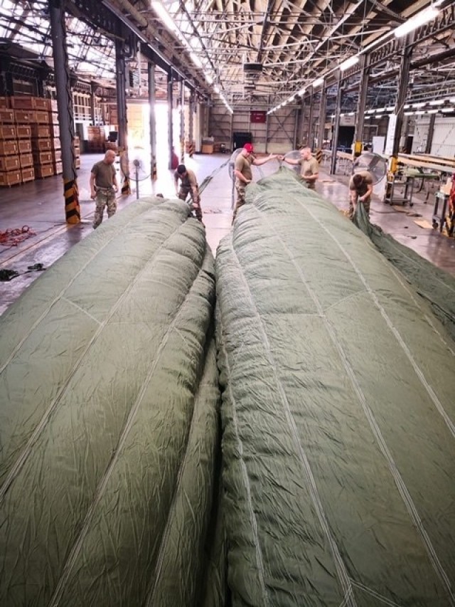 Riggers from the 4th Quartermaster Theater Aerial Delivery Company use an industrial fan to inflate the canopies of a 100 foot diameter G-11 Cargo Parachute System to route the centering lines. (Photo by Chief Warrant Officer 4 Brian Perinon,...
