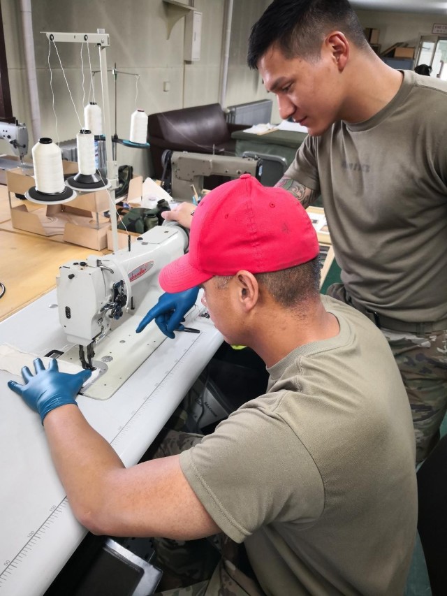 Chief Warrant Officer 2 Mervin Terre shows Spc. Ernie Ramirez the step by step process to fabricate cotton masks. Both are with the 4th Quartermaster Theater Aerial Delivery Company. The unit produced 95 high-quality face masks in the three-day period for U.S. Army Japan. (Photo by Chief Warrant Officer 4 Brian Perinon, Japan Support Team, AFSBn-NEA)