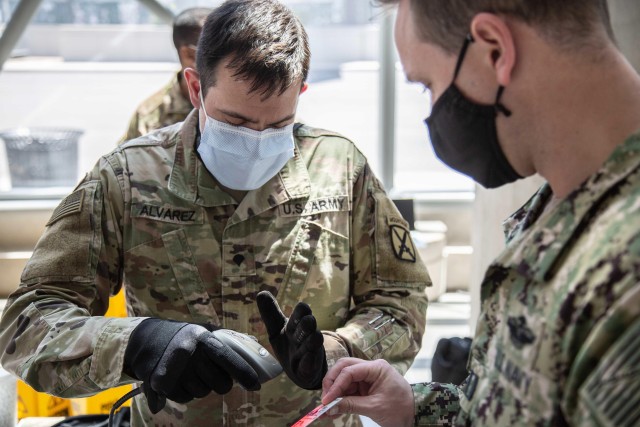 Army Spc. David Alvarez from 510th Human Resources Company, deployed from Fort Drum, N.Y., scans a sailors identification card while departing  the Javits New York Medical Station, in support of the Department of Defense COVID-19 response, May 10, 2020. U.S. Northern Command, through U.S. Army North, remains committed to providing flexible Department of Defense support to the Federal Emergency Management Agency for the whole-of-nation COVID-19 response. 