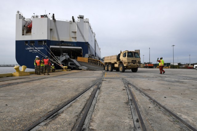 A contract worker directs a vehicle as it its backed onto the M/V Liberty Passion at Naval Weapons Station, Joint Base Charleston in Support of DEFENDER-Europe 20 March 10, 2020. DEFENDER-Europe 20 will exercise the deployment of a division-size combat-credible force from the United States to Europe, the drawing of equipment and the movement of personnel and equipment across the theater to various training areas. (U.S. Army photo/Kimberly Spinner)