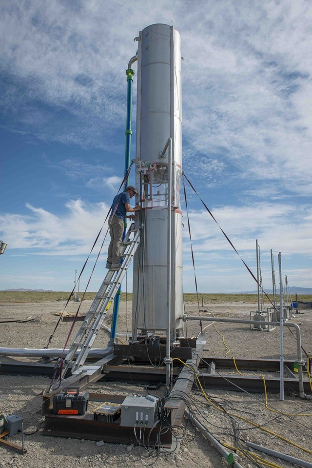 An engineer prepares the mock rocket body and its glass separator that keeps the liquid natural gas from the liquid oxygen. This body is about one meter in diameter; other larger tests have used 7-foot diameter bodies.
