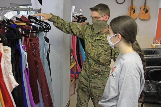 U.S. Army Pfc. Dillan Touchet, Alpha Company, 1st Battalion, 214th Aviation Regiment helps Nevaeh York, a Wiesbaden High School student pick out a prom dress during Operation Deploy The Prom on May 16 at the Club Beyond Youth Chapel on U.S. Army Garrison Wiesbaden Hainerberg. Touchet volunteered to assist with Operation Deploy The Prom by handing out ties and dresses to Wiesbaden High School students. (U.S. Army photo by Pfc. Raekwon Jenkins)