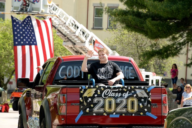 Leavenworth High School senior Cody Savage, driven by his father Storm Savage, waves to his mother, Rana, and his sister, Morgan, as he spots them among the graduation parade spectators May 15 on Scott Avenue. Photo by Prudence Siebert/Fort...