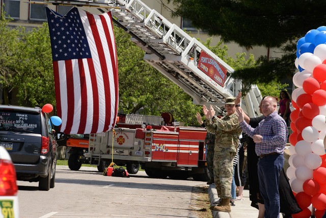 Combined Arms Center and Fort Leavenworth Commanding General Lt. Gen. James Rainey, Unified School District 207 Superintendent Keith Mispagel and other graduation parade spectators wave and cheer for graduating kindergartners, Patton Junior High...