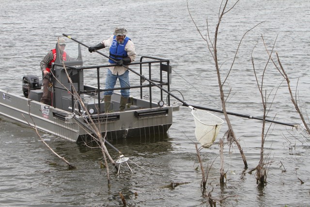 Walter Munsterman steers a fish shocking boat into shallow water on O’Connell Pond May 11, 2020, as Daniel Quickle looks for fish to net and bring into the boat. Fort Sill Natural Resources was out saving fish for transplant into other post...