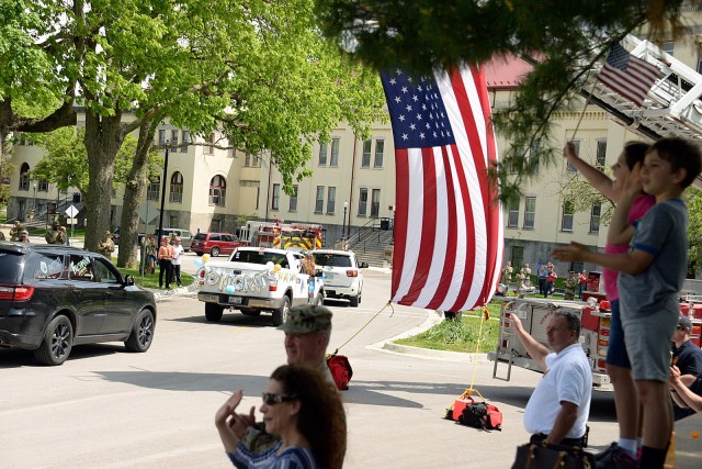 Community members wave and cheer for graduating kindergartners, Patton Junior High School ninth-graders and area high school seniors as they drive by in a graduation parade May 15 on Scott Avenue. Photo by Prudence Siebert/Fort Leavenworth Lamp