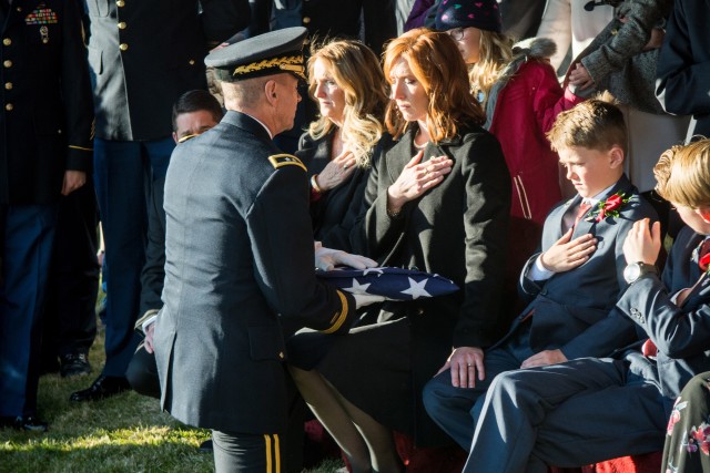 Army Maj. Gen. Jefferson Burton presents the flag that covered Army Maj. Brent Taylor’s casket to his widow, Jennie, in November 2018.