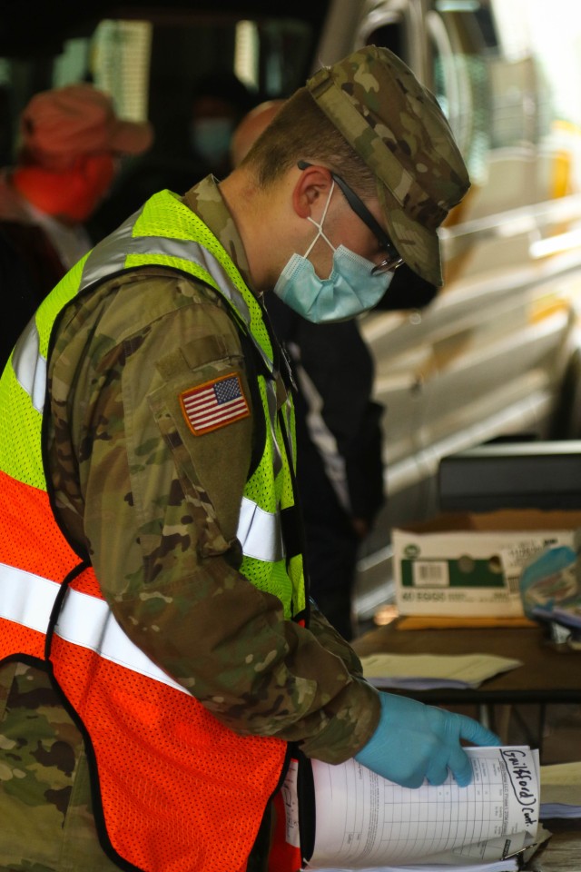 North Carolina Army National Guard Pvt. Christian Rogers, assigned to the 875th Engineer Company, reviews a document while working alongside North Carolina Emergency Management during a Personal Protective Equipment distribution in Central N.C., May 19, 2020. The NCNG is working with NCEM, N.C. Department of Health and Human Services and local food banks to help support COVID-19 relief efforts. (U.S. Army National Guard photo by Spc. Hannah Tarkelly, 382nd Public Affairs Detachment/Released).