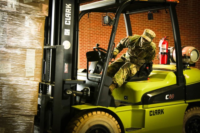 A North Carolina Army National Guard Soldier drives a forklift to move boxes while working alongside North Carolina Emergency Management during a Personal Protective Equipment distribution in Central N.C., May 19, 2020. The NCNG is working with NCEM, N.C. Department of Health and Human Services and local food banks to help support COVID-19 relief efforts. (U.S. Army National Guard photo by Spc. Hannah Tarkelly, 382nd Public Affairs Detachment/Released).