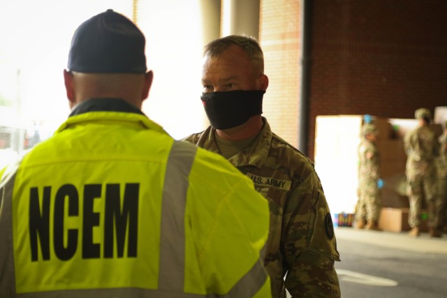 North Carolina Army National Guard Staff Sgt. Elbert Mote, assigned to the 878th Engineer Company, talks with a member of the North Carolina Emergency Management during a Personal Protective Equipment distribution in Central N.C., May 19, 2020. The NCNG is working with NCEM, N.C. Department of Health and Human Services and local food banks to help support COVID-19 relief efforts. (U.S. Army National Guard photo by Spc. Hannah Tarkelly, 382nd Public Affairs Detachment/Released).