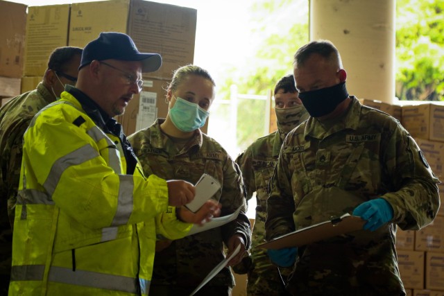 Soldiers of the North Carolina Army National Guard talk with a member of the North Carolina Emergency Management during a Personal Protective Equipment distribution in Central N.C., May 19, 2020. The NCNG is working with NCEM, N.C. Department of Health and Human Services and local food banks to help support COVID-19 relief efforts. (U.S. Army National Guard photo by Spc. Hannah Tarkelly, 382nd Public Affairs Detachment/Released).