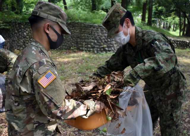 Spc. Nicko Pangilinan, left, assigned to the 35th Combat Sustainment Support Battalion, and Sgt. 1st Class Mitsuki Sato, assigned to the Bilateral Coordination Department, Japanese Ground Self-Defense Force, work together to clean up the area...