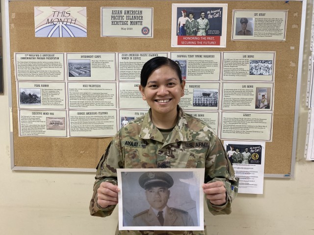 Sergeant First Class Pamela Ayaay holds a photo of her late grandfather, Lieutenant Colonel (RET) Antonio Ayaay, in front of the 160th Signal Brigade Equal Opportunity Board for Asian Pacific Islander Heritage Month.