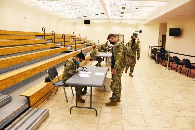 Fort Polk medical personnel process 4th SFAB Soldiers through a medical screening questionnaire station while following social-distancing and face-covering guidelines.