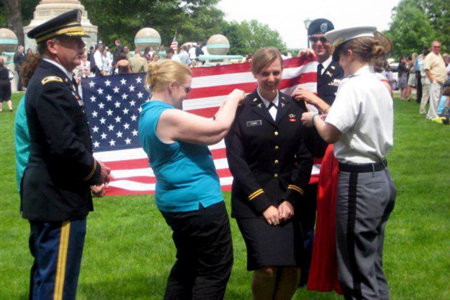 Then-Army 2nd Lt. Elyse Fiore Pierre poses as members of her family surround her and affix decorations to her uniform shortly after she received her commission as a medical officer in the Army in 2010.