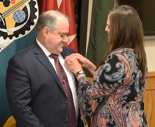 Renee Reilly places the Senior Executive Service pin on her husband, Dan Reilly, during a ceremony at Rock Island Arsenal, Ill., June 4.