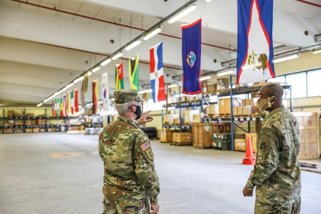 BAUMHOLDER, Germany - Brig. Gen. Gregory Brady, 10th Army Air and Missile Commanding General, talks with Chief Warrant Officer 3 Samuel Adeyame, a supply systems technician assigned to Echo Company 5th Battalion, 4th Air Defense Artillery Regiment at Smith Barracks, Germany June 8. The flags in the background are displayed in the E Co. Supply Support Activity building to represent where soldiers of the company are originally from. (Photo by Sgt. 1st Class Jason Epperson, 10th AAMDC PAO)